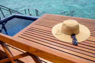 透き通った海とプール、その隣の机の上には麦わら帽子とサングラス