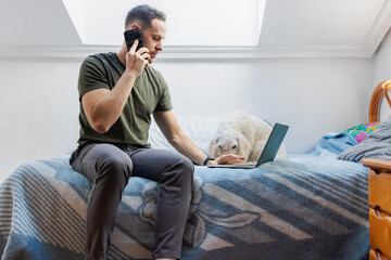 Fototapeta premium Freelancer working from home with pet using laptop and talking on phone