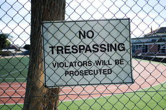 No trespassing sign attached to a large fence