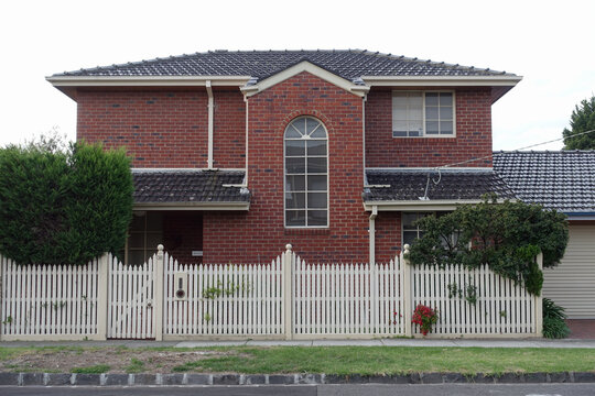 A double story suburban brick home with picket fence