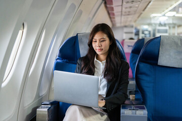 Business travel: Young woman concentrating while using a laptop on a flight