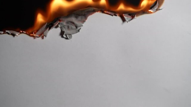 White paper burning on a black background, close up. Paper burns, smoke and turns into ashes. Fire and paper
