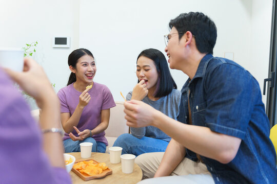 Group of friends enjoying snacks and laughter during a casual gathering in a modern living room