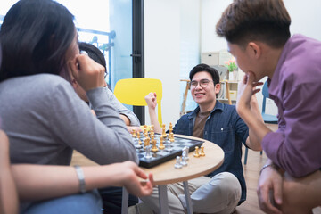 Group of friends enjoying a lively chess game while socializing in a cozy modern space during afternoon gathering