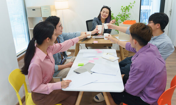 Team members celebrating success with drinks during a collaborative meeting in a modern office space