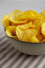 Homemade Kettle Cooked Potato Chips with Salt in a Bowl, side view. Close-up.