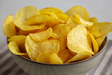 Homemade Kettle Cooked Potato Chips with Salt in a Bowl, side view. Close-up.