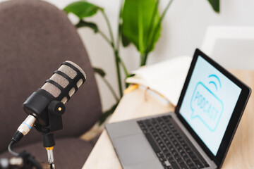 Podcast setup in modern office featuring microphone and laptop for interviews and educational...
