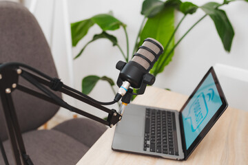 Podcast setup in a modern office featuring microphone and laptop for educational interviews and...
