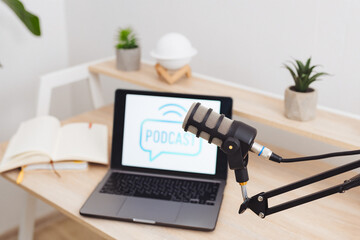 Podcast setup in a modern office featuring a microphone, laptop, and educational materials for...