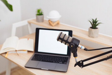 Podcast recording setup in a modern office environment featuring a microphone and laptop on a minimalist desk