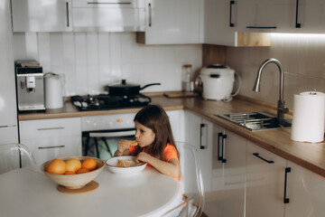 Young Girl Eating Fruit Breakfast in a Modern Kitchen Interior Setting