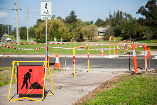 Roadwork sign on footpath before taped off work-site area