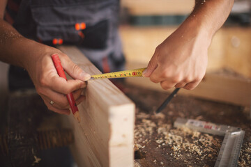 Young carpenter measuring wooden board