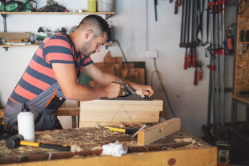 Young carpenter plaining wooden table