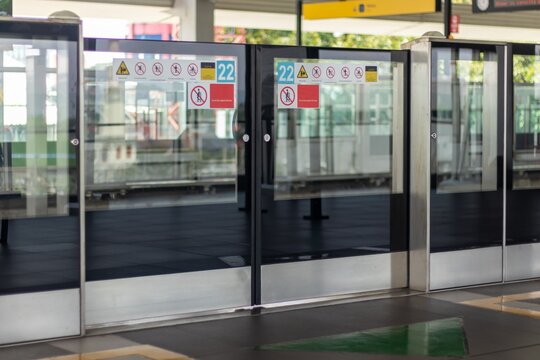 Platform Screen Door (PSD) or Platform Edge Door (PED) with various safety warning stickers at the Mass Rapid Transit train station Jakarta