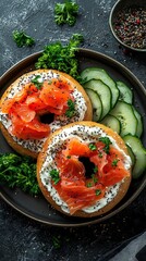 Two appetizing bagels topped with cream cheese, smoked salmon, poppy seeds, and parsley are arranged with sliced cucumber on a dark plate.
