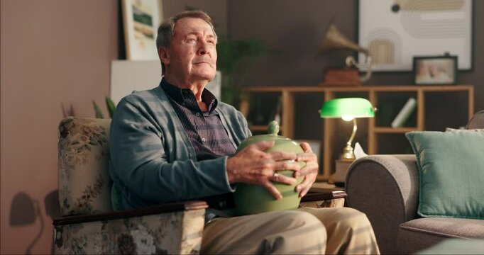 Thinking, urn and sad with old man on sofa for reflection, mourning and retirement. Memory, mental health and grief mindset with senior person in living room at home for depression, loss and death