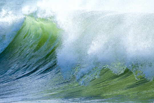 A green wave curls and breaks over Snapper Rocks.