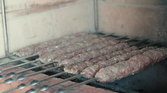 Sizzling lula kebab grilling on metal skewers over hot charcoal, traditional caucasian meat cooking inside brick oven with rising smoke, aromatic flavors wafting