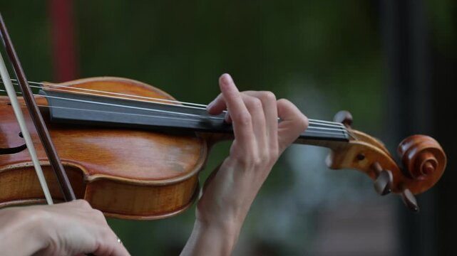 Violinist performing with intense focus, moving bow gracefully across strings in captivating slow motion closeup revealing musical passion and technical mastery