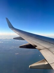 Fototapeta premium Airplane wing view with blue sky and ocean.