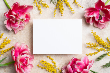 Blank paper card mockup with copy space, beautiful flowers decoration on beige background, flat lay