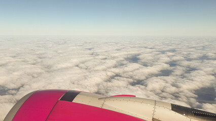 Scenic view of airplane wing against expansive cloudscape during daytime flight through clear blue sky captured in mid-air journey