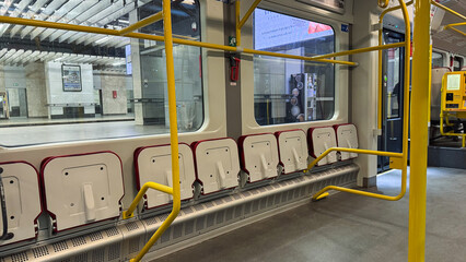 Modern subway interior with vibrant yellow bars and empty gray seats in a sleek urban train station focusing on clean lines and architecture