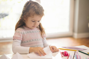 Naklejka premium Cute little girl crafting boat from papper