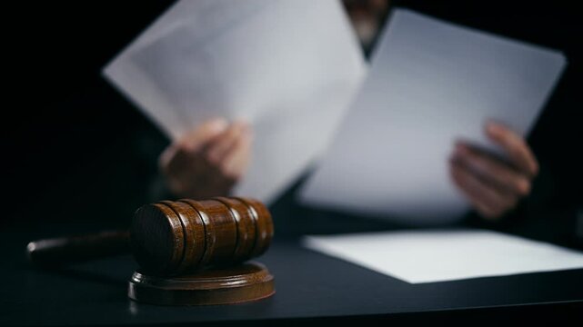 Judge working with legal papers in courtroom, gavel on desk, judicial system