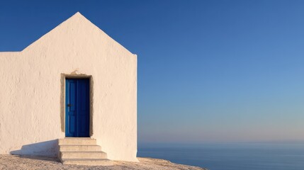 Whitewashed building with a blue door overlooking the calm sea at sunset, serene atmosphere