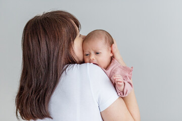 Mother comforting newborn baby on shoulder. Copy space