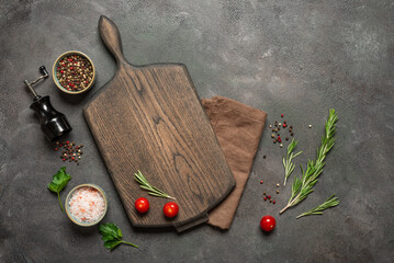 Culinary background with wooden cutting board, spices, herbs and vegetables