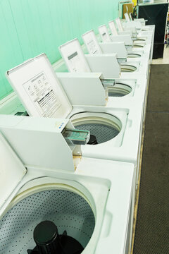 A row of washing machines with their lids up in a launderette