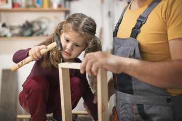 Father and daughther making wooden frame in workshop