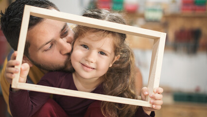 Father and daughther making wooden frame in workshop