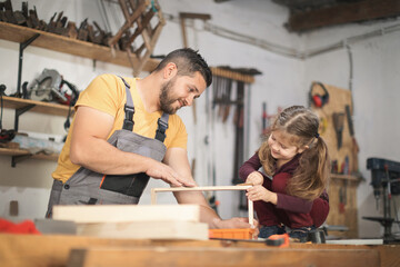 Father and daughther making wooden frame in workshop