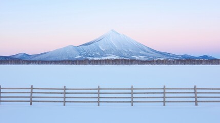 Fototapeta premium Snowy landscape with a volcano and wooden fence at dawn