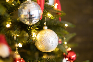 Close-up of silver Christmas baubles on a decorated tree with warm lights. Festive holiday season...