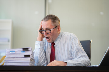 Stressed caucasian maturebusinessman working in the office.