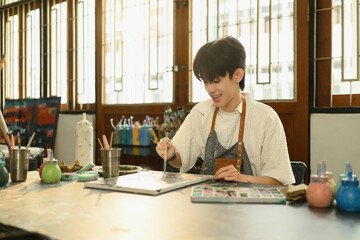 A Young LGBT Artist Smiling While Painting in Studio