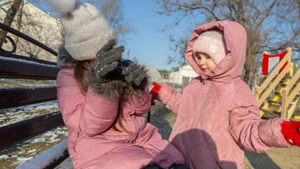 Two little children, quarreling and ready to beat each other crying during their walking in winter.