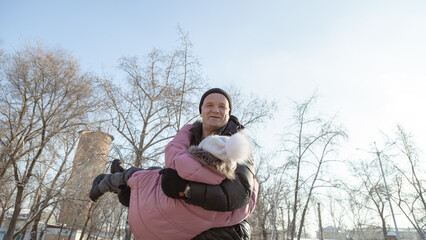 Grandfather playing with her granddaughter on the playground in the park in winter