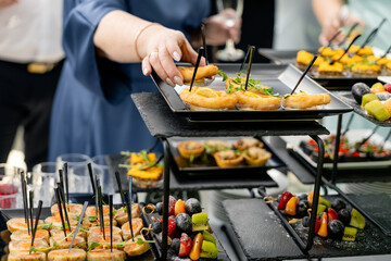 Hand collecting food from buffet table at party