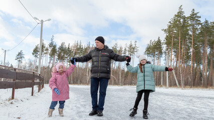 Little girls with her grandfather walking in park on snowy winter day