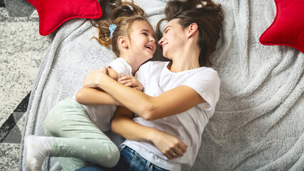 Overhead view of a mother and her daughter laughing happily on the floor at home