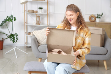 Young woman unpacking parcel box with new high heels at home
