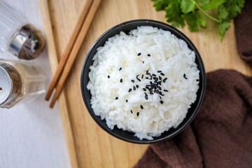Cooked white rice or steamed rice with black sesame on top  in a black  bowl, top view food table