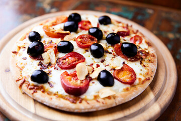 Pizza with salami and mozzarella cheese, jalapeno pepper and black olives. Wooden background. Soft focus. Close up.	